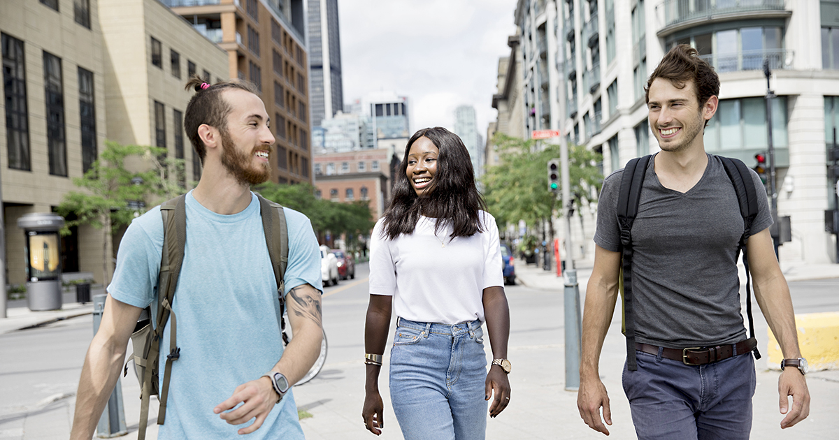 Étudiants souriants marchant en ville, ambiance décontractée et urbaine.