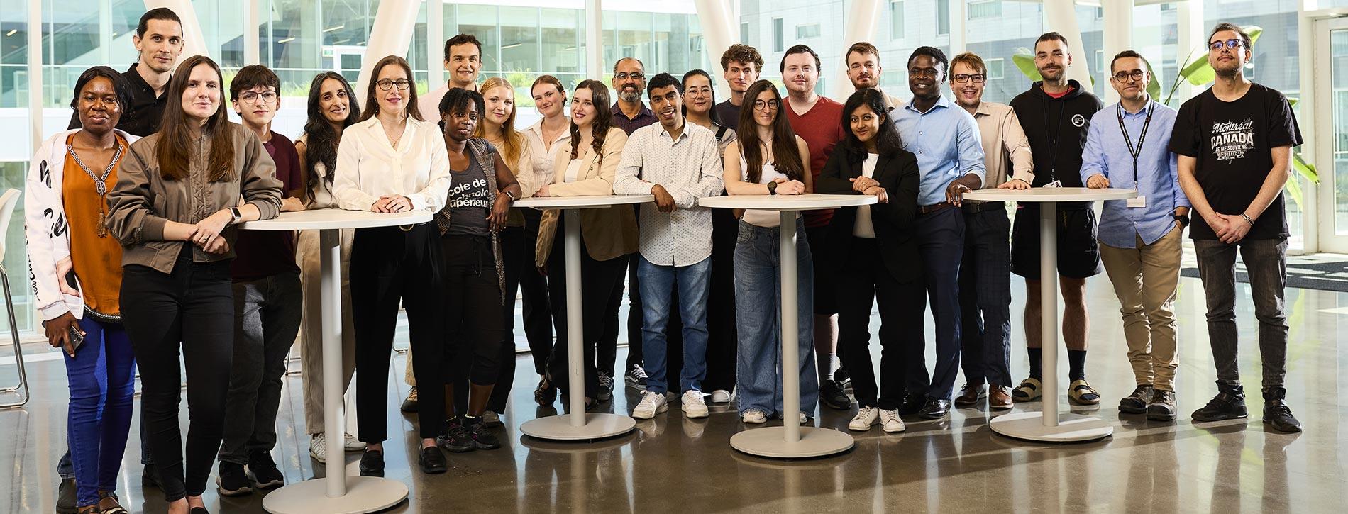L'équipe de recherche de la Chaire de recherche du Canada sur les matériaux de construction multifonctionnels durables, composée d'une vingtaine d'étudiants et d'étudiantes de tous les niveaux, entoure la titulaire de la chaire, la professeure Claudiane Ouellet-Plamondon, dans le hall d'un pavillon de l'ÉTS.