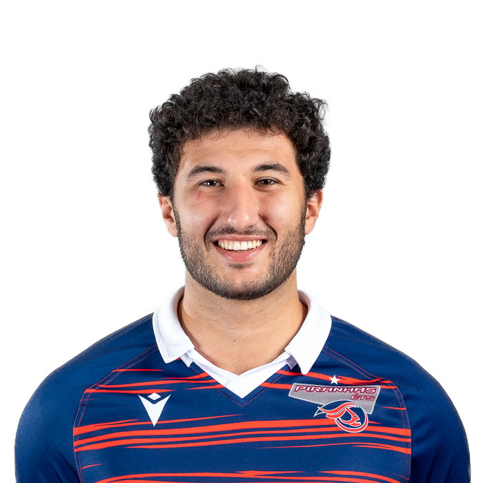 Étudiant souriant en maillot sportif avec emblème d'école, représentant dynamisme et jeunesse en technologie.