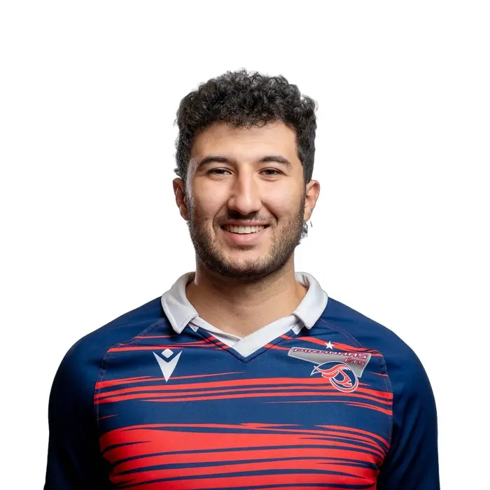 Étudiant souriant en maillot sportif avec emblème d'école, représentant dynamisme et jeunesse en technologie.