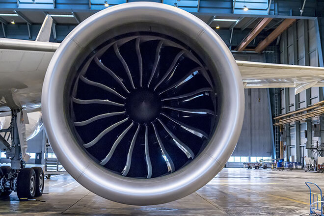 A close-up view of a jet engine showcasing its intricate turbine design in a spacious maintenance hangar.