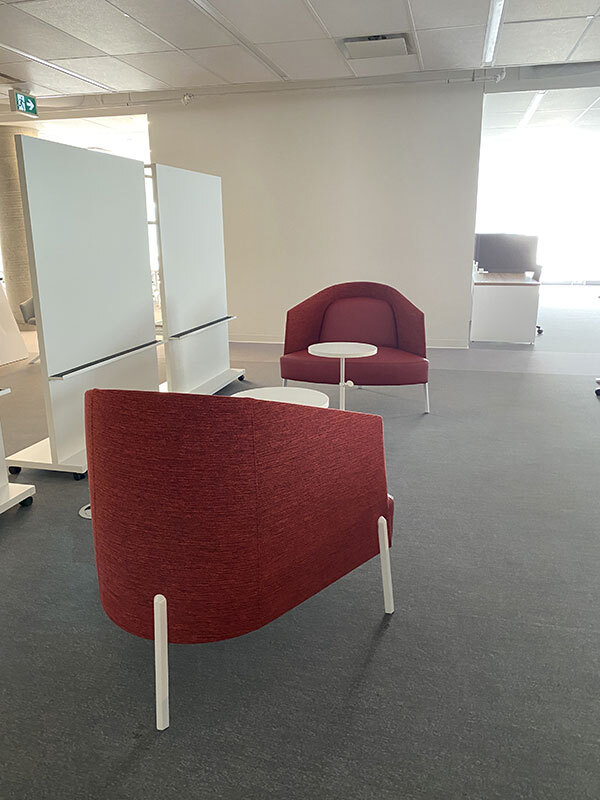 Espace moderne avec fauteuils rouges et tableaux blancs pour travaux d'équipe.