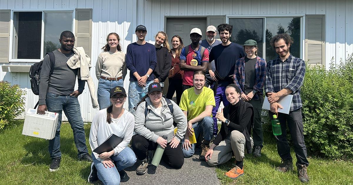 Groupe d'étudiants rassemblés devant un bâtiment, souriants et présentant un esprit collaboratif. Ambiance conviviale et dynamique.