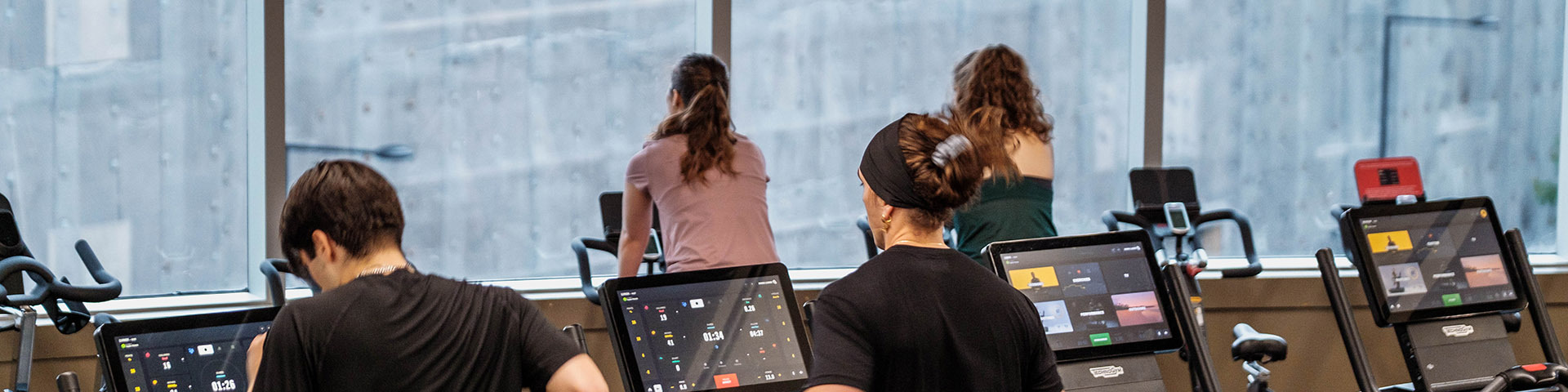 Des étudiants s'entraînent ensemble dans un espace moderne, profitant de machines de fitness avec une vue captivante à l'extérieur.