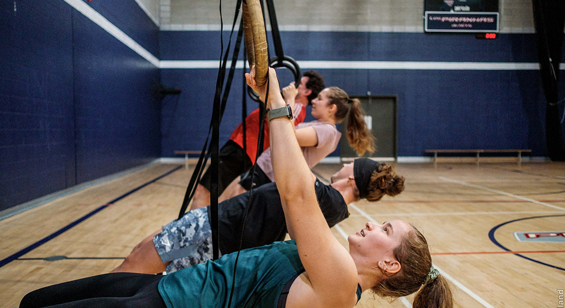 Des étudiants s'entraînent en groupe dans un gymnase, utilisant des cordes pour renforcer leur condition physique.