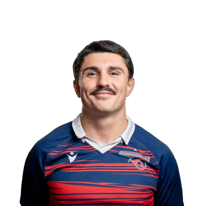 Étudiant souriant en tenue sportive, arborant une moustache.