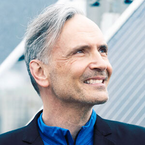 Un homme au sourire chaleureux regarde l'horizon, semblant réfléchir à des idées innovantes dans un cadre moderne.