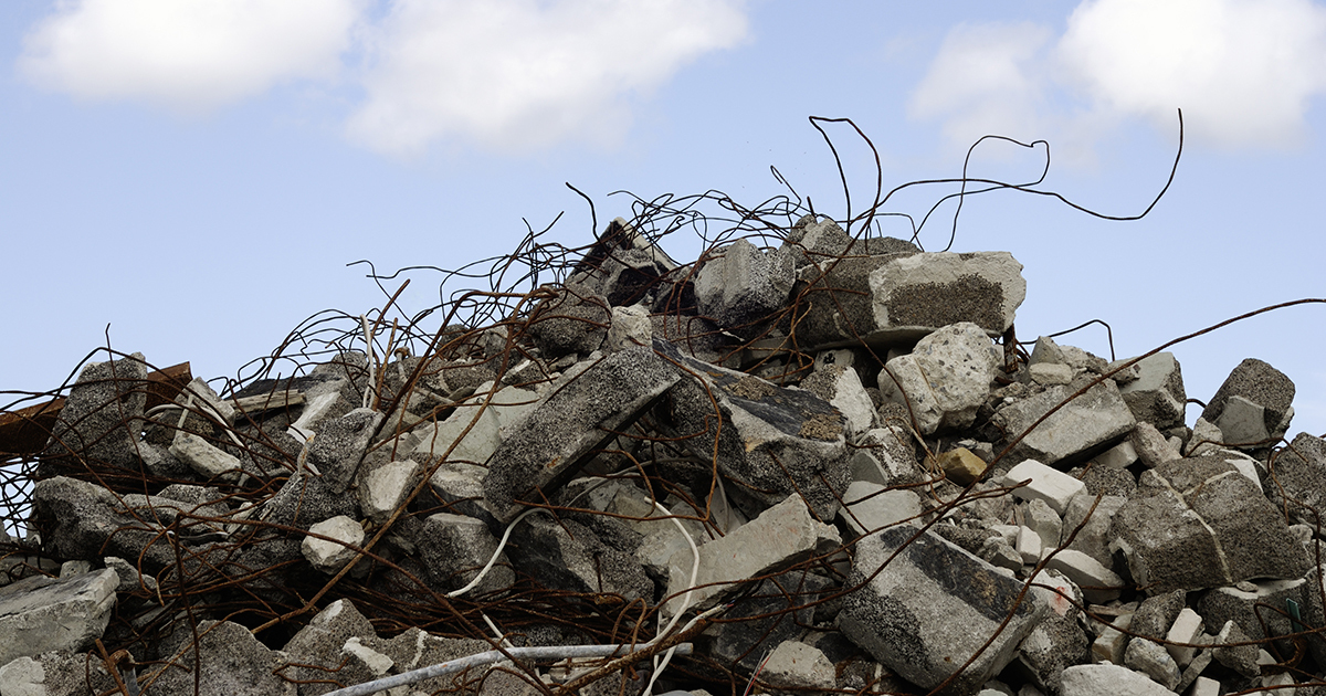 Pile of rubble and twisted rebar against a blue sky, highlighting demolition aftermath or recycling.