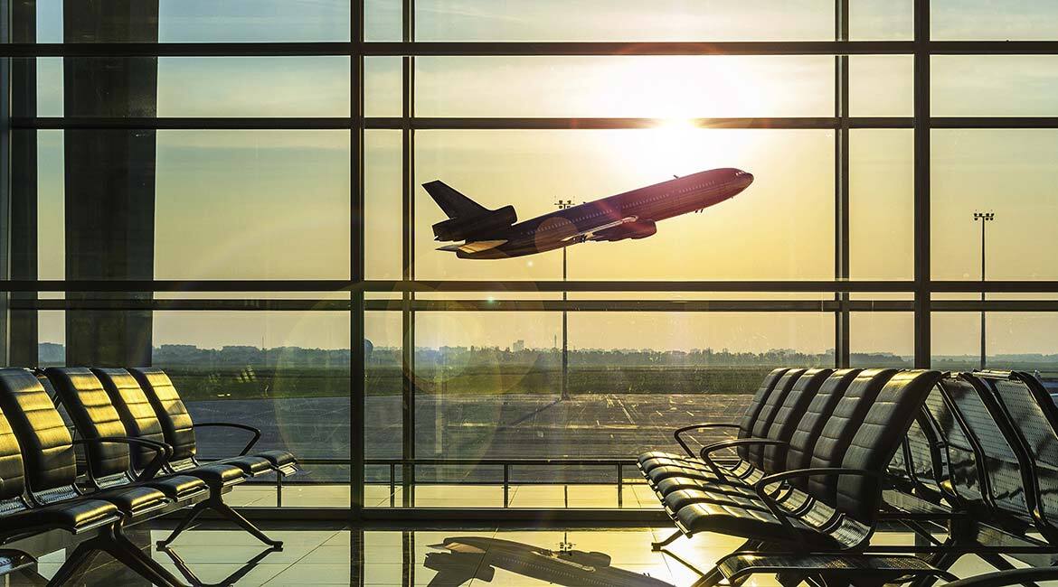 Aéroport au lever du soleil, avion décollant, sièges vides en attente de voyageurs.
