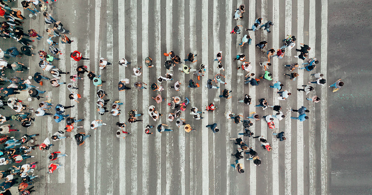 A bustling crosswalk filled with diverse pedestrians, showcasing urban life and the movement of people in a busy city environment.