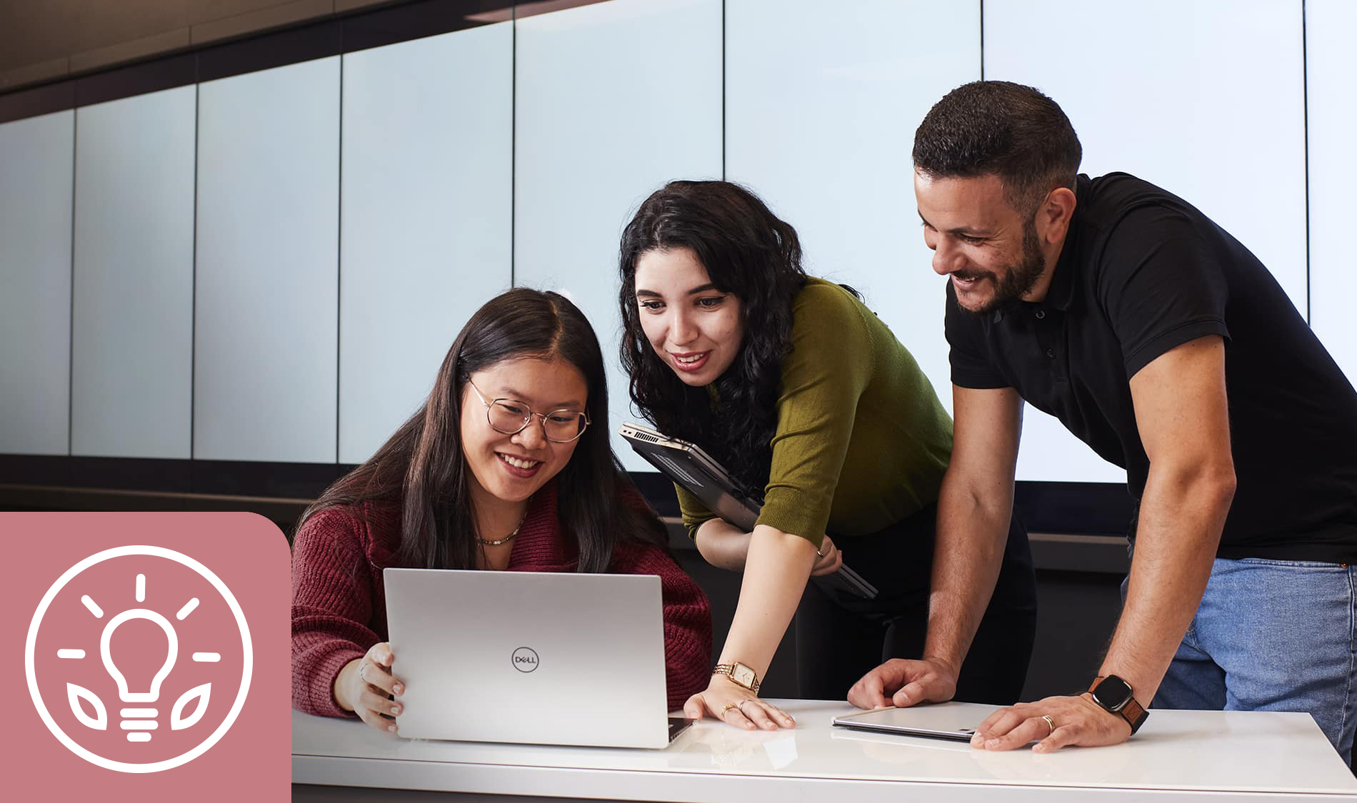 Un groupe d'étudiants collabore, échangeant des idées avec enthousiasme autour d'un ordinateur portable dans un environnement moderne.