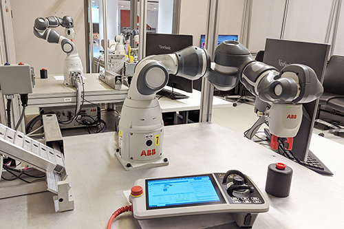 Laboratoire moderne avec robots industriels ABB et interfaces de programmation pour formation en robotique.