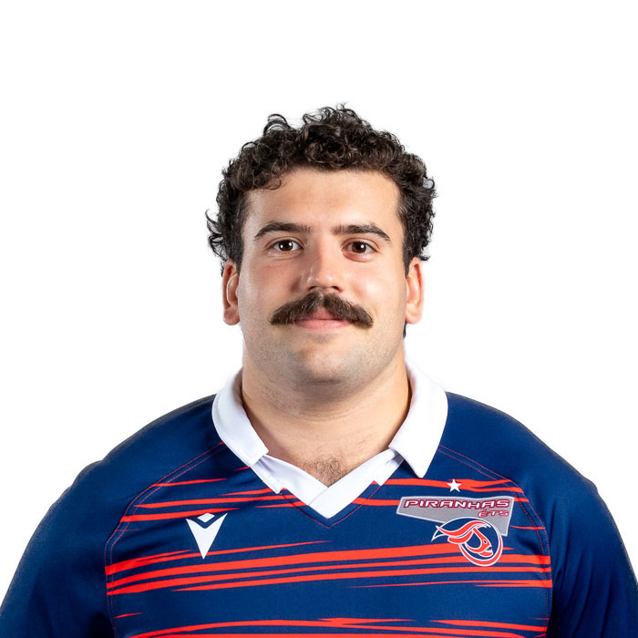 Étudiant en technologie, portant maillot sportif, moustache notable.