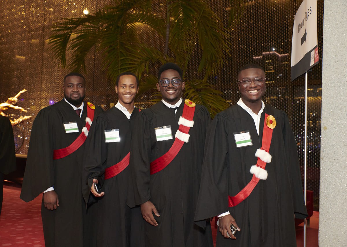 Cinq diplômés en toges posent avec le sourire, célébrant leur réussite dans un cadre élégant et festif.