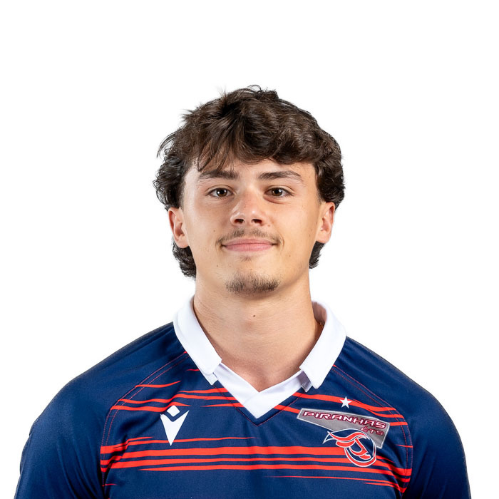 Étudiant en technologie, portant un maillot de l'équipe des Piranhas, affichant un sourire confiant et déterminé.