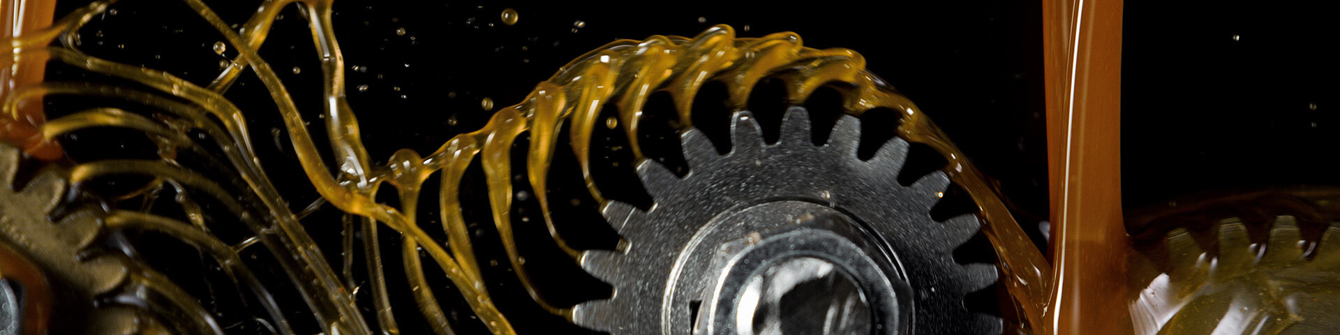 Engrenage sous un jet d'huile, symbolisant la mécanique et l'innovation technologique.