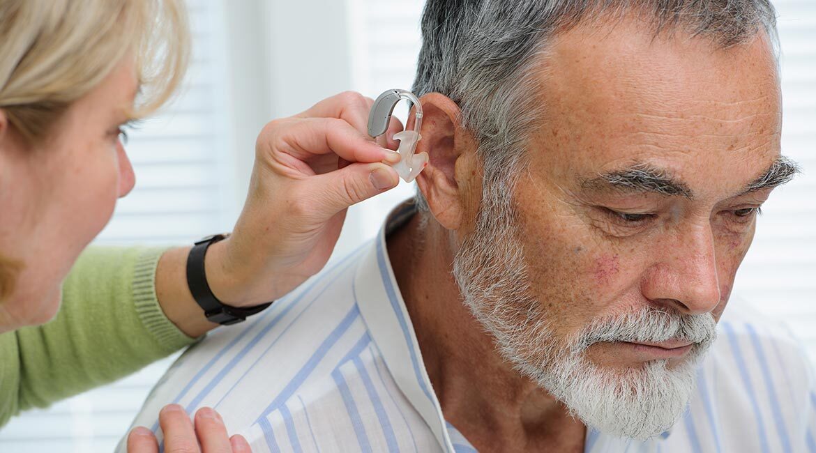 Ajustement d'une prothèse auditive sur une personne âgée.