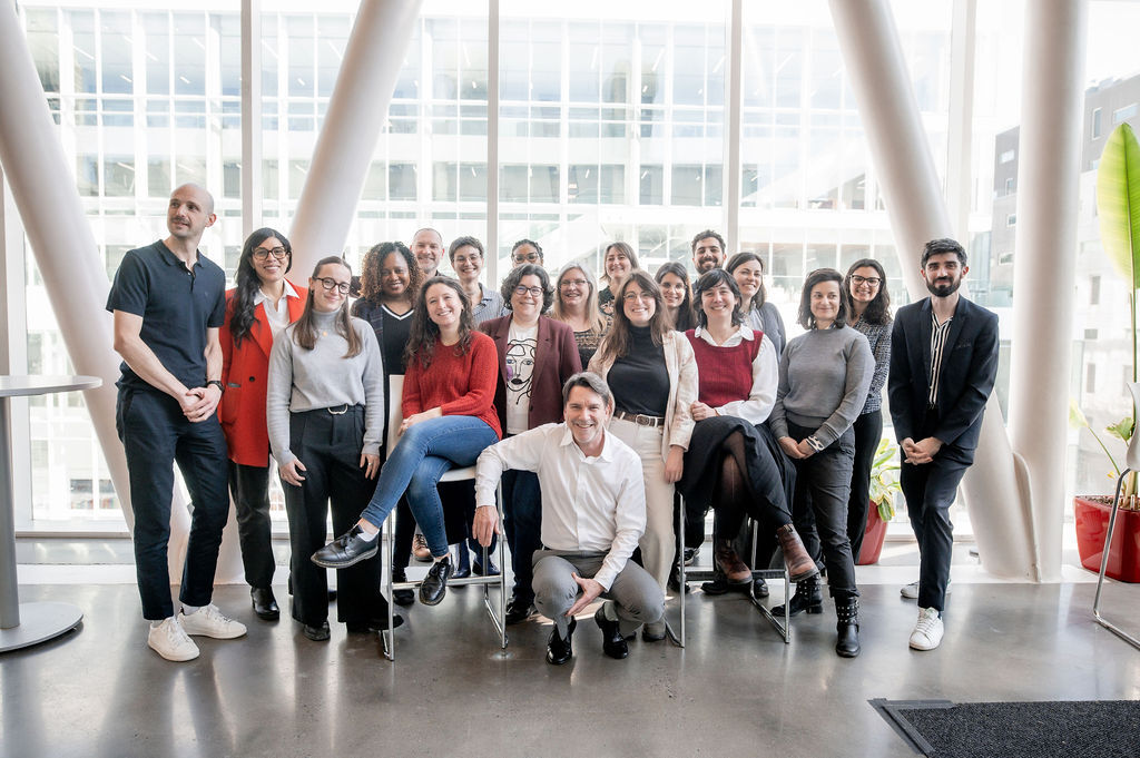 Équipe dynamique et souriante réunie dans un espace moderne, mettant en valeur la collaboration et l'innovation.