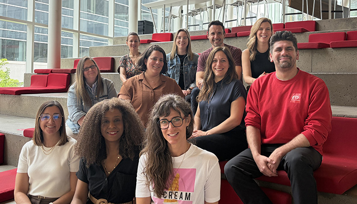 A diverse group of smiling professionals standing in a modern space, symbolizing collaboration and innovation.