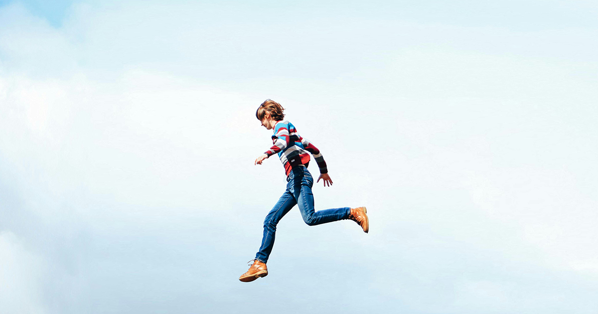 Un enfant en pleine course, captivé par l'aventure, sur fond de ciel clair et lumineux. Énergie et liberté s'entremêlent.