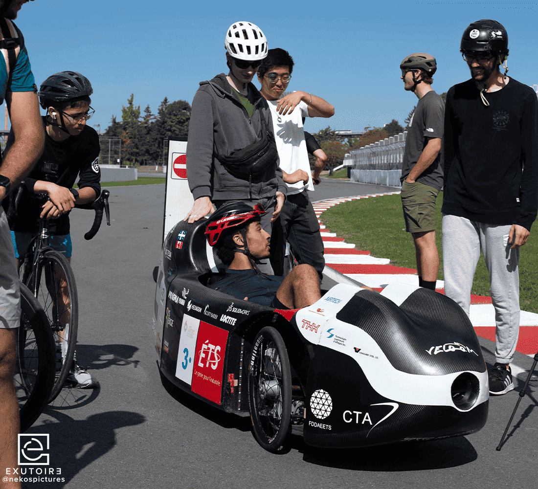 Des étudiants entourent un prototype de véhicule innovant sur un circuit, mettant en avant leur passion pour les technologies et l'ingénierie.
