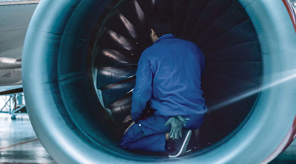 Technicien en aéronautique inspectant un moteur d'avion.