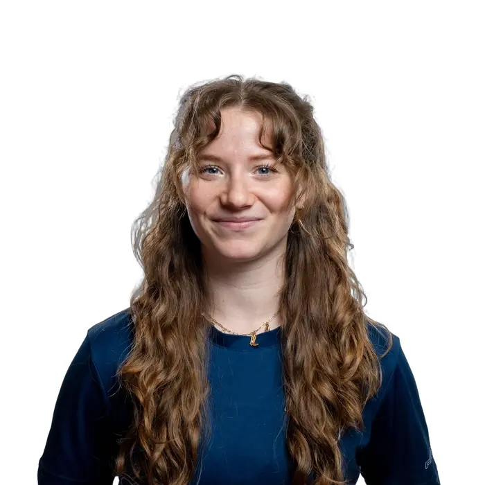 Étudiante souriante en chemise rouge, les cheveux frisés, représentant l’esprit positif et dynamique de l'Université en technologie supérieure.