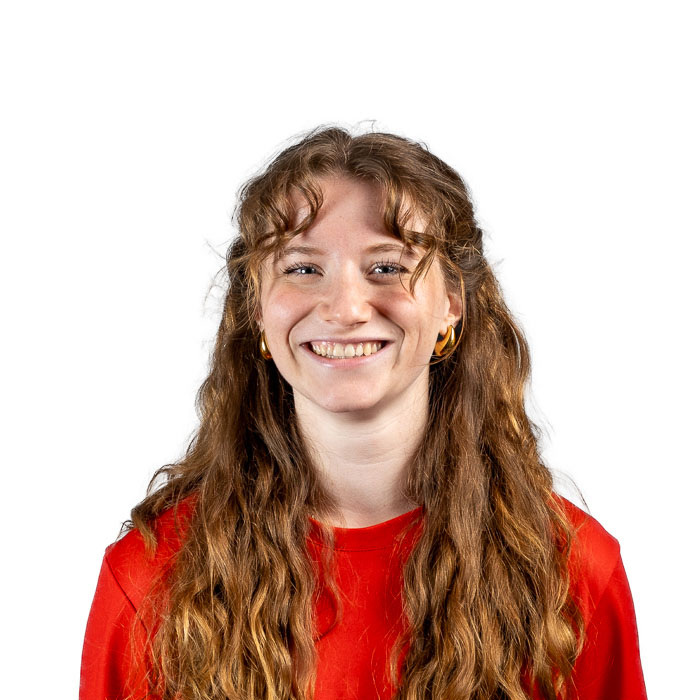 Étudiante souriante en chemise rouge, les cheveux frisés, représentant l’esprit positif et dynamique de l'Université en technologie supérieure.