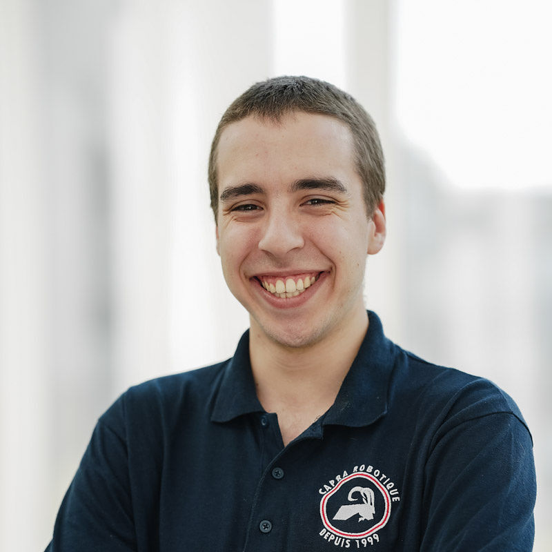 Étudiant souriant portant un polo bleu, représentant une passion pour la robotique et l'innovation technologique.