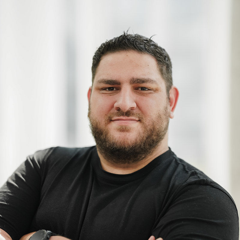 Élève confiant, arborant un t-shirt noir, il se tient avec assurance, prêt à relever des défis dans le domaine technologique.