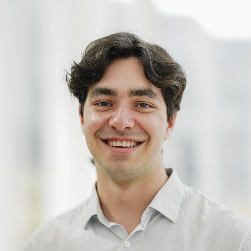 Sourire chaleureux et regard engageant, un jeune homme affiche sa joie de vivre dans un cadre lumineux et moderne.