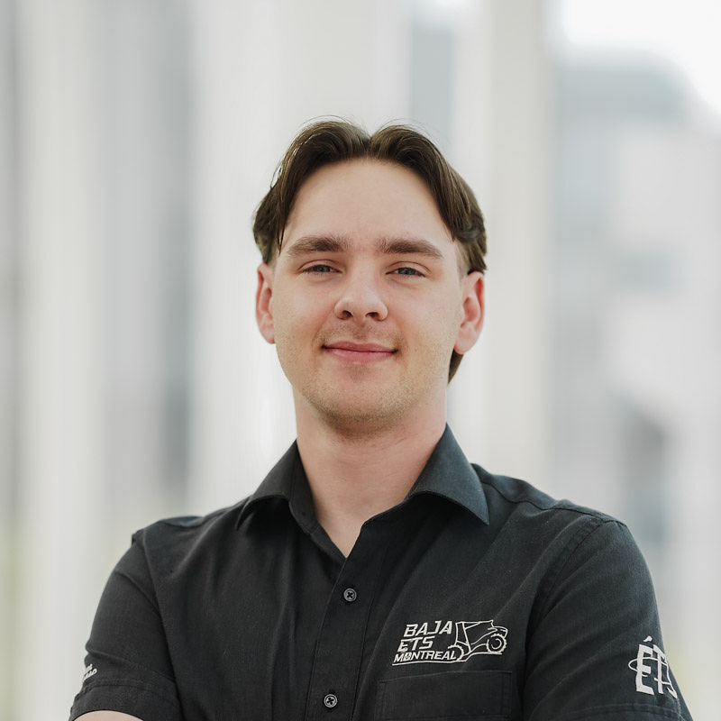 Étudiant passionné d'ingénierie, membre de l'équipe Baja ETS Montréal, déterminé et souriant dans un environnement moderne.