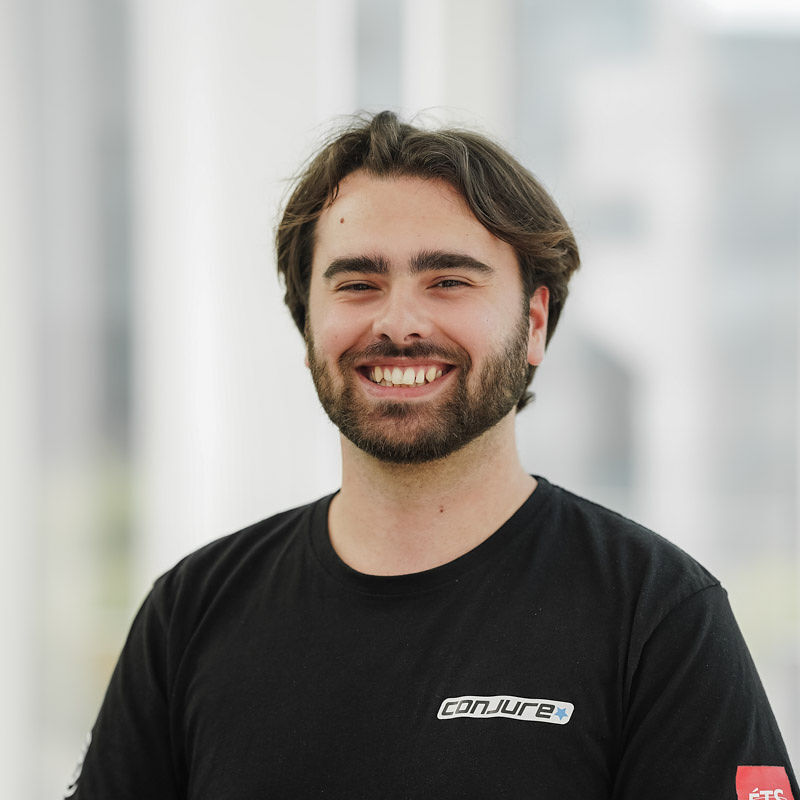 Étudiant souriant de l'Université en technologie, portant un t-shirt noir, illustrant l'engagement et le dynamisme de la communauté.