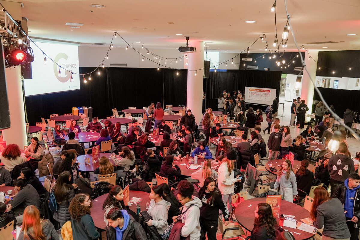 Événement vibrant et convivial, réunissant des étudiants autour de tables, avec une ambiance chaleureuse et des lumières suspendues.