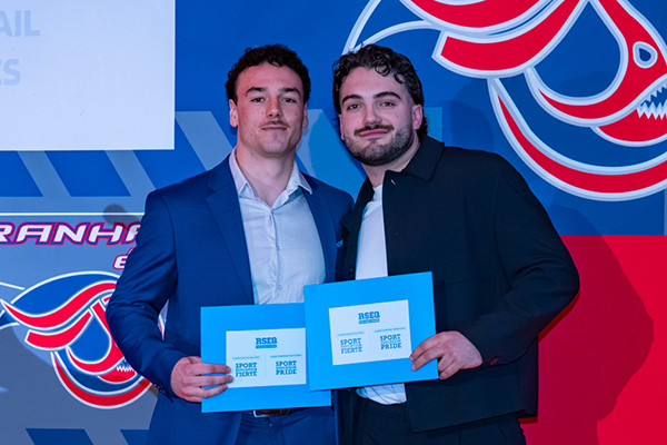 Deux étudiants souriants posent fièrement avec des prix, célébrant leurs réalisations académiques dans un environnement festif.