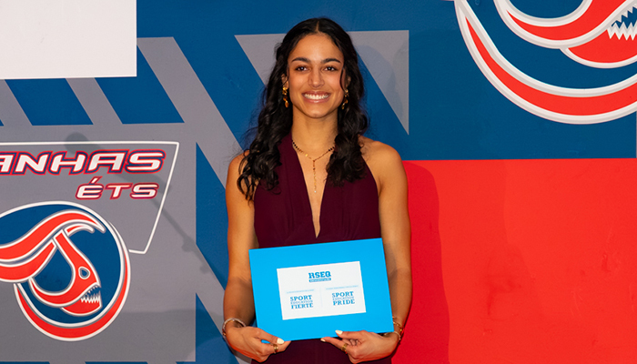 Étudiante souriante en tenue élégante, tenant un prix pour son excellence sportive, mettant en valeur l'engagement académique et athlétique.