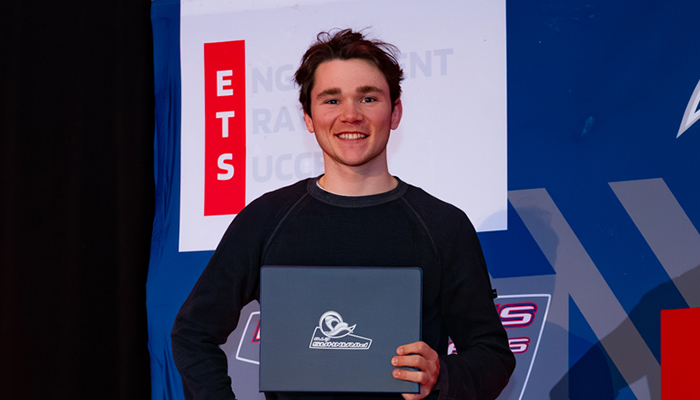 Un étudiant souriant tient un prix, témoignant de ses réussites académiques à l'Université de Technologie Supérieure.