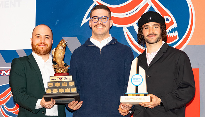 Trois étudiants célébrant des réussites sportives, tenant des trophées au sein de l'Université en technologie supérieure.