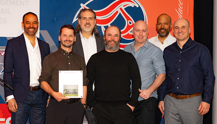 Un groupe de professionnels posant ensemble lors d'un événement, affichant un certificat et un fond aux couleurs vives.