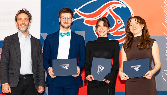 Célébration de diplômés entourés d'un enseignant, affichant fierté et réussite lors d'un événement universitaire.