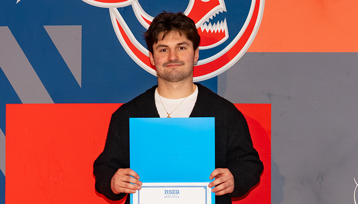 Un étudiant souriant tient un diplôme, célébrant sa réussite académique dans un cadre festif et coloré.