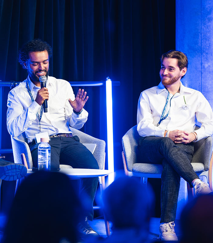 Deux intervenants partagent des idées lors d'un événement, illustrant l'échange de connaissances dans un cadre technologique.