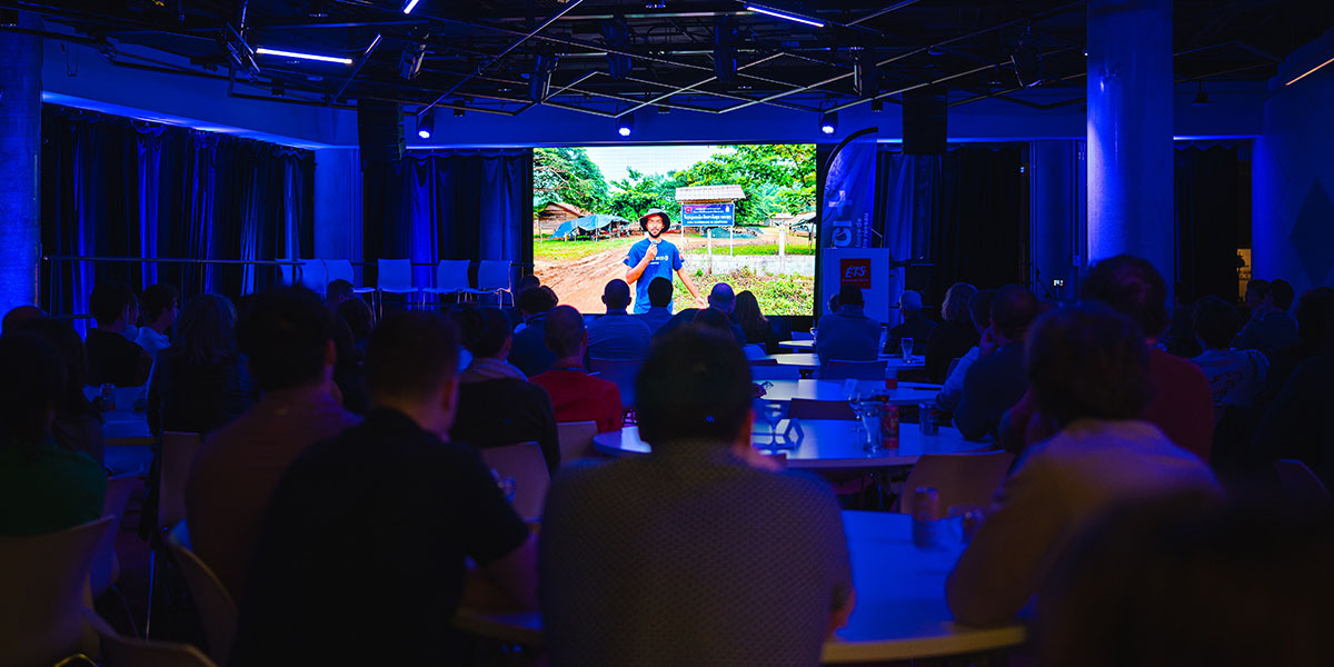 Un séminaire captivant avec un intervenant sur scène, entouré d'un public attentif, dans une ambiance moderne et entouré de lumière bleue.