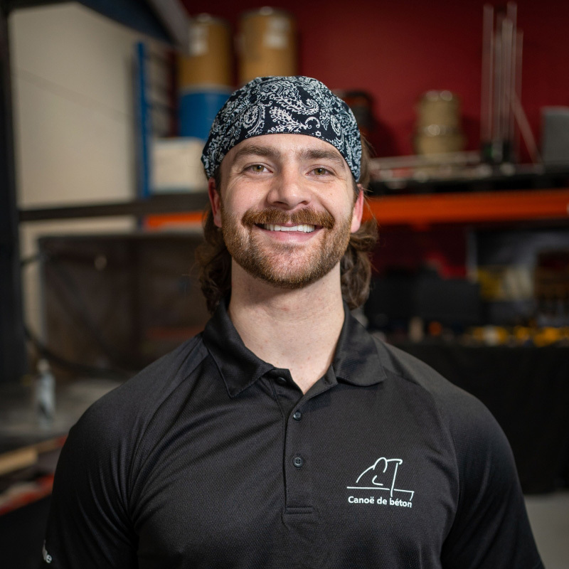 Un étudiant souriant en tenue de travail, prêt à relever des défis techniques dans un environnement axé sur l'innovation.