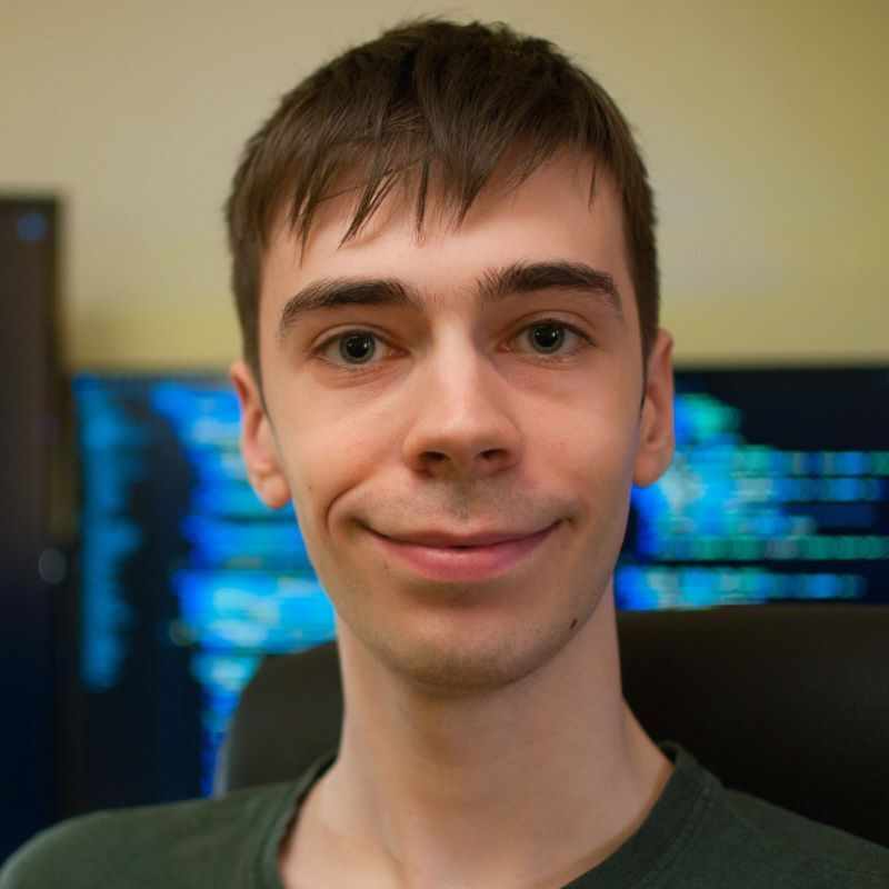 Jeune homme souriant devant des écrans, engagé dans l'apprentissage et la pratique des technologies avancées. Ambiance studieuse et dynamique.