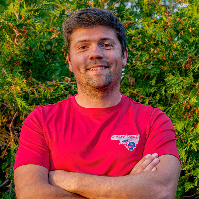 Homme avec sweat-shirt des Piranhas ETS, souriant en extérieur.