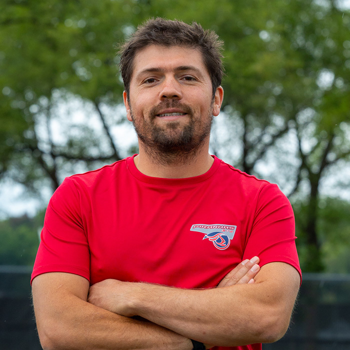 Homme avec sweat-shirt des Piranhas ETS, souriant en extérieur.