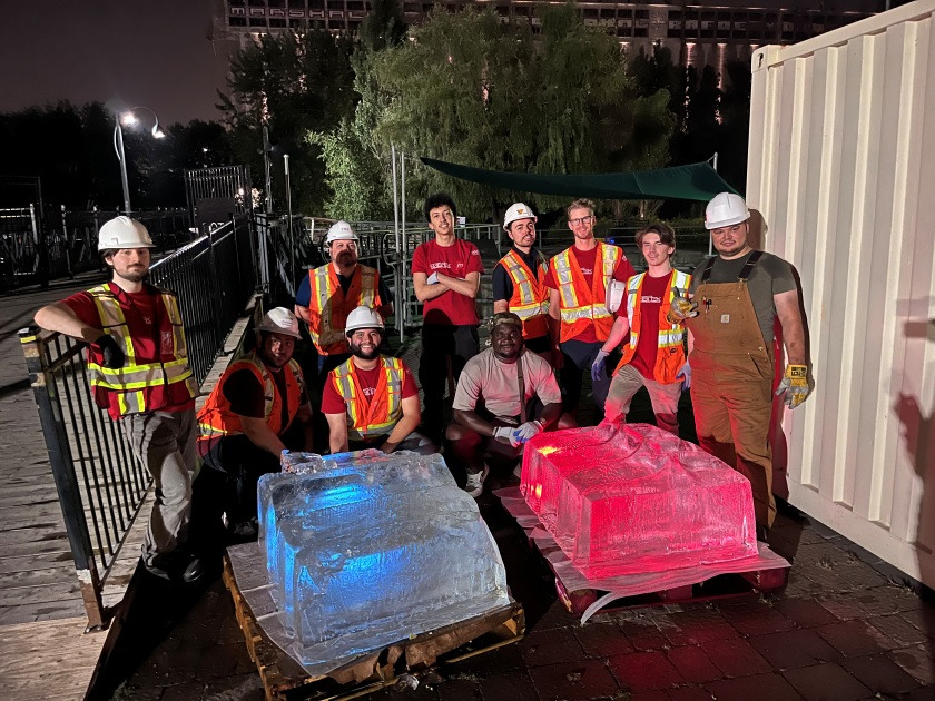 Des étudiants en tenue de sécurité posent avec des blocs de glace colorés, illustrant un projet technologique nocturne inspirant.