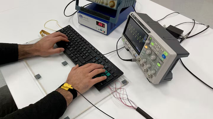 An individual operates a keyboard while interacting with electronic equipment, showcasing hands-on learning in technology.