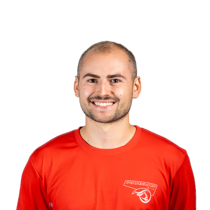 Étudiant souriant en t-shirt rouge, prêt à relever de nouveaux défis en technologie. Ambiance dynamique et conviviale.